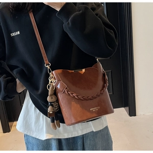Detailed view of brown PU leather bucket bag with woven handle and plush bunny charm