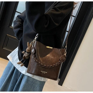 Detail of dark brown vintage PU bucket bag with woven handle and bunny pendant