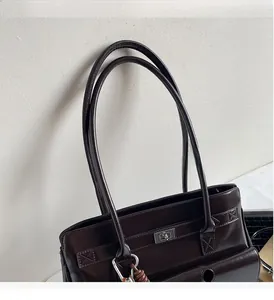 Detail der dunkelbraunen Kunstleder-Tasche mit silbernem Drehverschluss und Schultergurt