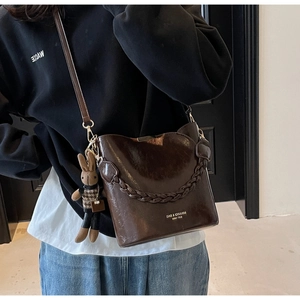 Elegant dark brown glossy PU leather bucket bag with braided handle and cute charm