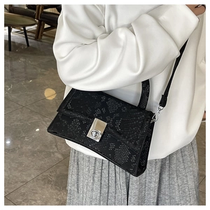 Detail of black snake-pattern embossed leather handbag with a silver rotating metal lock