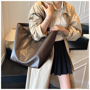 Detailansicht einer großen dunkelbraunen Leder-Tote-Bag an einem Model im lässigen Innenraum