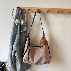 Detail of dusty pink suede hobo bag with black leather straps and plush puppy charm