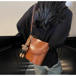 Detail of brown PU leather bucket bag with woven handle and a cute rabbit charm