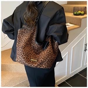 Mannequin portant un grand sac cabas à motif léopard avec des anses noires dans un escalier