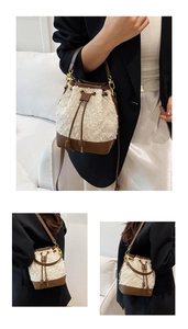 Detail of cream fleece bucket bag featuring brown leather trim and gold metal eyelets