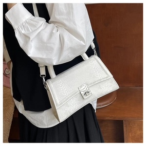 Detail of white crocodile pattern structured handbag with silver metallic twist lock