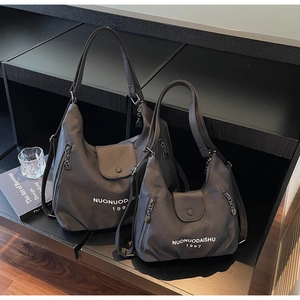 Macro shot of large and small charcoal grey nylon hobo bags with silver zipper details