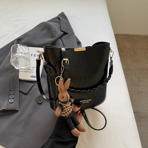 Detail of black PU leather bucket bag with metal buckle and cute bunny charm accessory