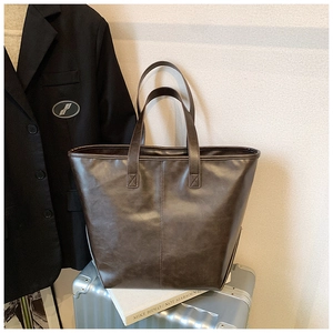 Detail der dunkelbraunen Kunstleder-Tote Bag mit Vintage-Textur auf einem Silberkoffer