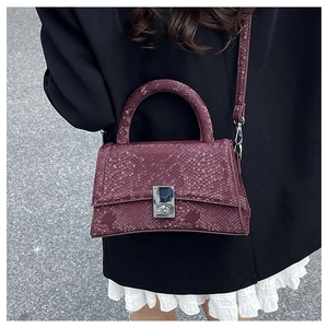Detail view of burgundy snake-pattern handbag with silver square metal lock closure
