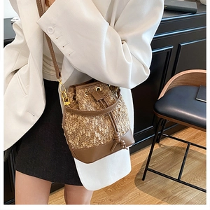 Detail view of contrast stitching bucket bag featuring brown faux fur and leather textures
