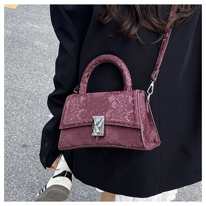 Detailed macro view of deep purple snakeskin textured leather handbag with silver lock
