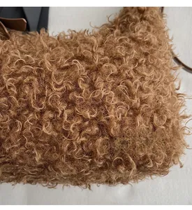 Gros plan sur la texture bouclée en peluche et la bandoulière en cuir du sac marron