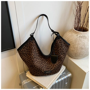 Détail du sac cabas léopard avec lanières en cuir noir sur une valise argentée