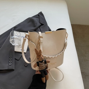 Detail of cream PU leather bucket bag with gold hardware and plush rabbit charm accessory