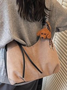 Brown suede tote bag with black strap and puppy charm shown on model in retro style