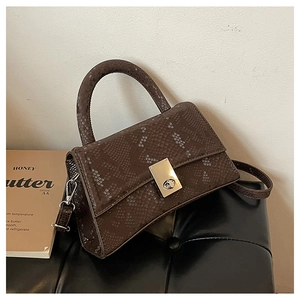 Detail of a brown faux snakeskin handbag with silver metal twist lock and curved handle