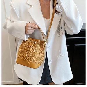 Detail of yellow tweed and leather bucket bag with drawstring worn with white blazer