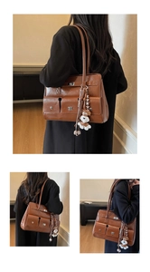 Detail der braunen Vintage-Ledertasche mit mehreren Taschen, Drehverschlüssen und Anhänger