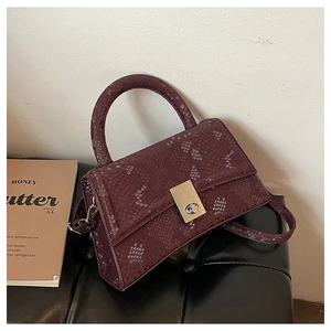 Detail of dark purple snakeskin texture handbag with silver rectangular twist lock