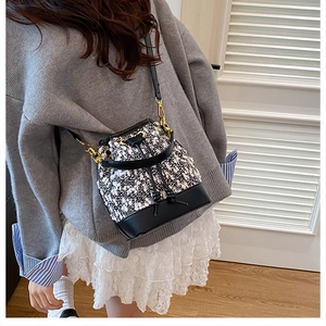 Chic black and white tweed bucket bag featuring leather base and elegant gold metal hooks