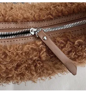 Détail du zip argenté lisse et de la lanière en cuir sur sac en peluche marron