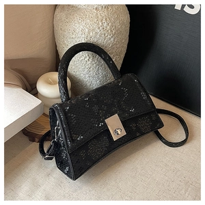 Detail shot of black snake-embossed leather handbag with silver metal turn-lock closure