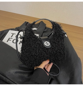 Dettaglio di borsa nera in peluche con chiusura a scatto argento e texture morbida