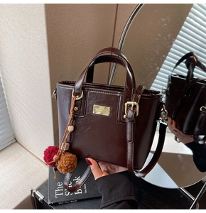 Dettaglio della borsa a secchiello in pelle cerata marrone con hardware dorato