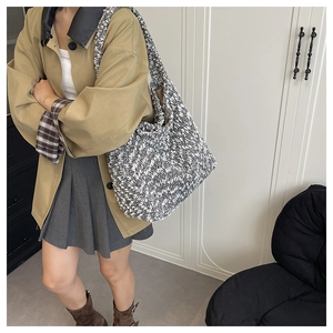 Detail view of large tweed tote bag with textured knit fabric worn with a casual trench coat