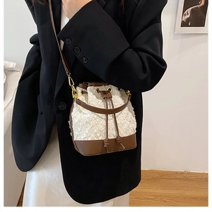 Detail view of a brown and white plush bucket bag with leather strap on a fashion model