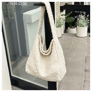Detail of soft cream plush fleece hobo tote bag texture on a black door handle