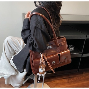 Detailansicht braune Leder-Tote-Tasche mit Außentaschen und Plüsch-Hundeanhänger