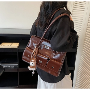 Detail einer dunkelbraunen, glänzenden Einkaufstasche mit Taschen und Hundeanhänger