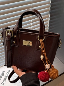Elegante borsa a secchiello in pelle marrone scuro con ciondolo e dettagli dorati