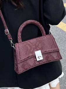 Fashionable burgundy snake-textured trapezoid handbag with silver twist lock and strap