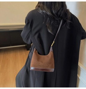 Détail du sac hobo marron en patchwork avec lettrage embossé et finition mate texturée