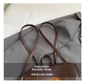 Détail des bretelles réglables et de la texture litchi sur le sac à dos en cuir brun