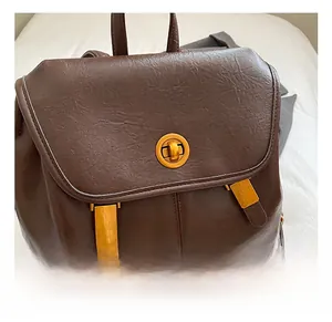 Gros plan sur le fermoir rotatif doré et les boucles métalliques du sac à dos marron