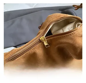Close-up of golden metal zipper and brown suede texture on a stylish shoulder bag