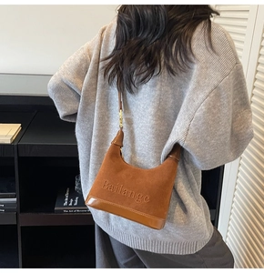 Détail du sac hobo en daim marron avec relief du logo Bailange et boucles dorées