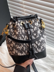 Fashionable black and white tweed bucket bag with leather trim and gold hardware accents