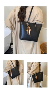 Détail d'un sac cabas tissé noir avec un pendentif à pompon perlé de style ethnique
