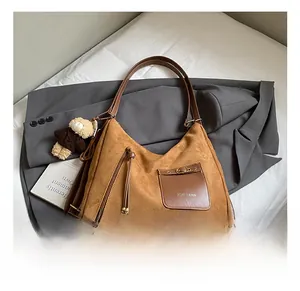 Detail of brown faux suede shoulder bag with plush bear charm and ZSKE PARIS logo pocket