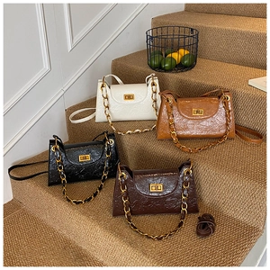 Close-up of four glossy pleated leather shoulder bags with bold gold chain straps