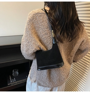 Détail du sac en daim noir et cuir avec boucles dorées et lettrage embossé sur le corps