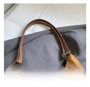 Detail of brown suede hobo bag featuring synthetic leather handle and vintage bronze hooks