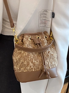 Retro khaki tweed bucket bag with brown leather strap worn by a model in a suit