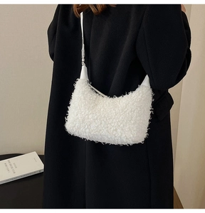 Détail du sac hobo en peluche blanche porté avec un manteau en laine noir chic